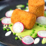 Fried crumbed goat cheese with sweet pea puree, radishes and spring onions.
