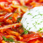 Close-up homemade borscht soup with beetroot, beef and cabbage served with sour cream.