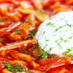 Close-up homemade borscht soup with beetroot, beef and cabbage served with sour cream featuring a title overlay.