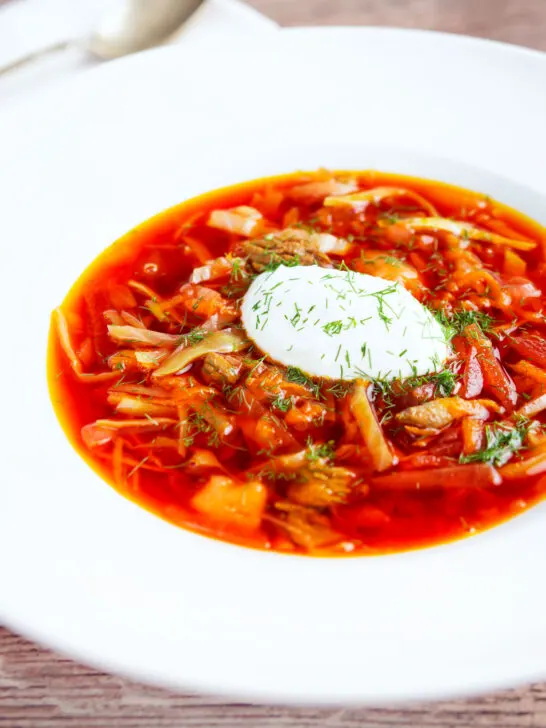 Homemade borscht soup with beetroot, beef and cabbage served with sour cream and dill.