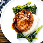 Overhead thick cut honey mustard pork chops with roasted tenderstem broccoli and mashed potato.