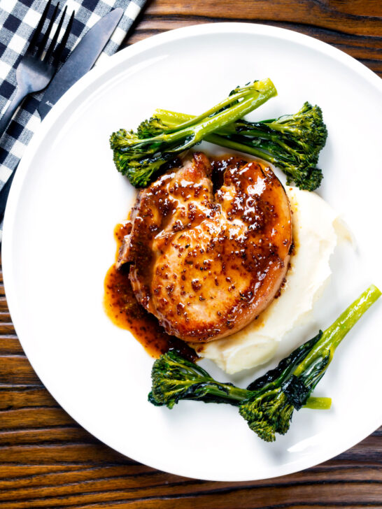 Overhead thick cut honey mustard pork chops with roasted tenderstem broccoli and mashed potato.