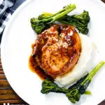 Overhead thick cut honey mustard pork chops with roasted tenderstem broccoli and mashed potato featuring a title overlay.