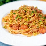 Hot dog spaghetti topped with crispy onions and mustard breadcrumbs.