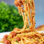 Hot dog pasta with a mustard and crispy onion crumb being eaten with a fork.