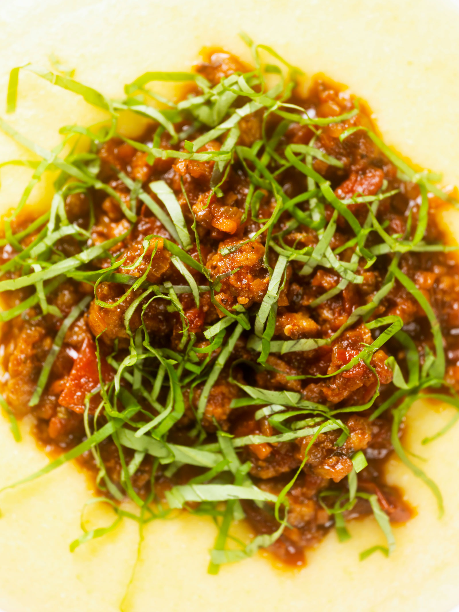 Overhead close-up sausage ragu made with Italian sausages and tomatoes served with polenta.