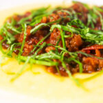 Close-up sausage ragu made with Italian sausages and tomatoes served with polenta.