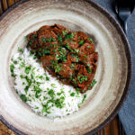 Overhead kaleji masala or lambs liver curry serve with basmati rice and naan bread.