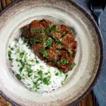 Overhead kaleji masala or lambs liver curry serve with basmati rice and naan bread.
