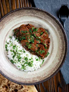 Overhead kaleji masala or lambs liver curry serve with basmati rice and naan bread.