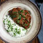 Overhead kaleji masala or lambs liver curry serve with basmati rice and naan bread featuring a title overlay.