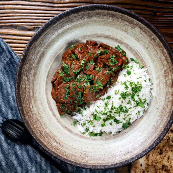 Indian lamb liver curry or kaleji masala served with rice, naan and fresh coriander.