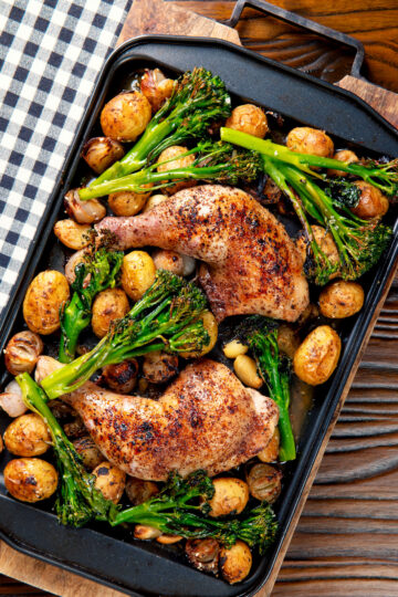 Overhead chicken leg tray bake with preserved lemon, shallot, potato, garlic and broccoli.