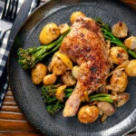 Overhead baked chicken leg with preserved lemons, potatoes, garlic and broccoli.