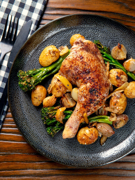 Overhead baked chicken leg with preserved lemons, potatoes, garlic and broccoli.