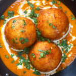 Close-up overhead malai kofta, vegetarian paneer and potato "meatball" curry featuring a title overlay.