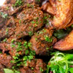 Overhead close-up peri peri chicken livers served with beetroot salad and wedges.