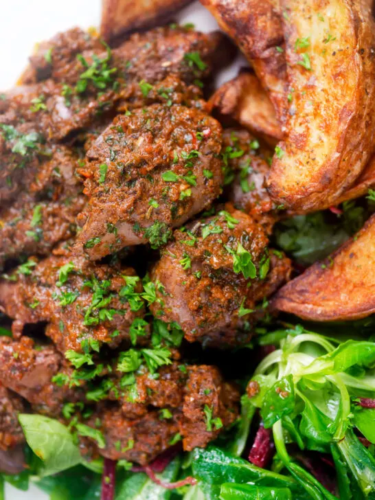 Overhead close-up peri peri chicken livers served with beetroot salad and wedges.