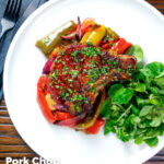 Overhead tray baked paprika pork chop with red wine and honey bell peppers and onions featuring a title overlay.