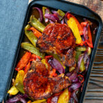 Overhead pork chop traybake with peppers and onions cooked in red wine vinegar and honey.