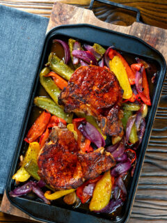 Overhead pork chop traybake with peppers and onions cooked in red wine vinegar and honey.