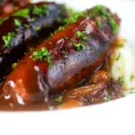 Close up slow cooker pork sausages in a mustard and BBQ sauce.