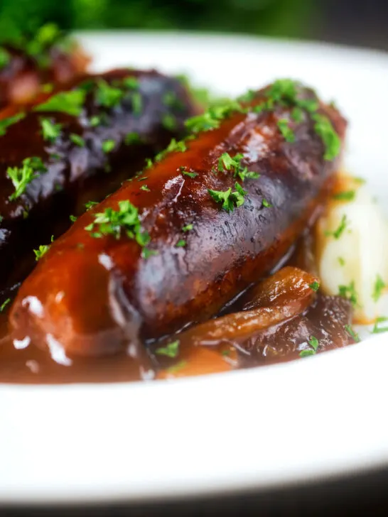 Close up slow cooker pork sausages in a mustard and BBQ sauce.