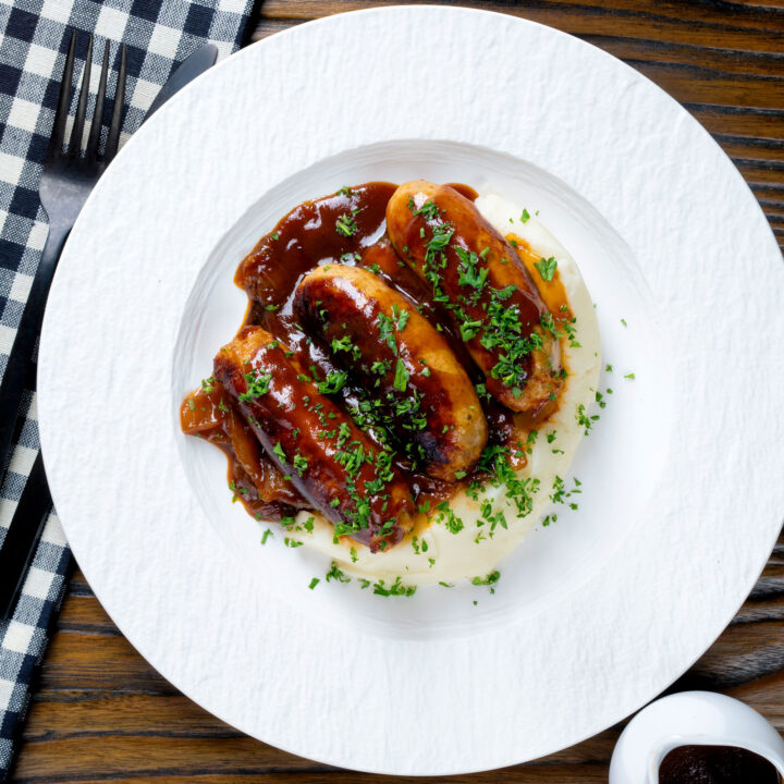 Slow cooker pork sausages with onions and BBQ sauce served with mashed potato.