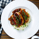 Overhead slow cooker pork sausages in a mustard and BBQ sauce.
