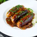 Slow cooker pork sausages in a mustard and BBQ sauce served with mashed potato.