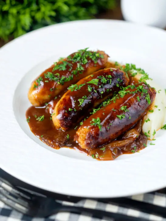 Slow cooker pork sausages in a mustard and BBQ sauce served with mashed potato.