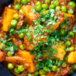 Close-up overhead Indian aloo matar curry with potatoes and peas.