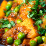Close-up Indian aloo mutter curry with potatoes and peas.