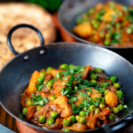 Indian aloo matar curry with potatoes and peas served with naan bread.