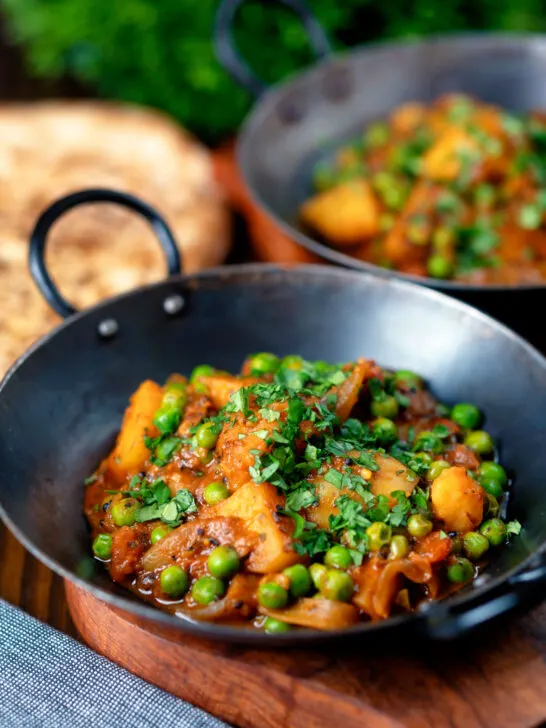 Indian aloo matar curry with potatoes and peas served with naan bread.