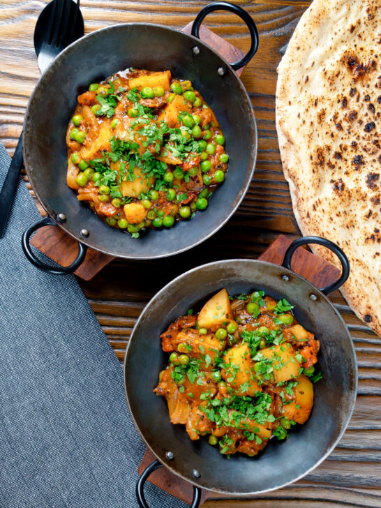 Overhead Indian aloo matar curry with potatoes and peas served with naan bread.