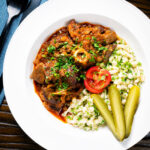 Overhead Hungarian birkapörkölt or mutton stew served with nokedli.