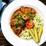 Overhead Hungarian birkapörkölt or mutton stew served with nokedli featuring a title overlay.