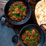 Overhead Anglo Indian chicken dopiaza curry served with chapatis.