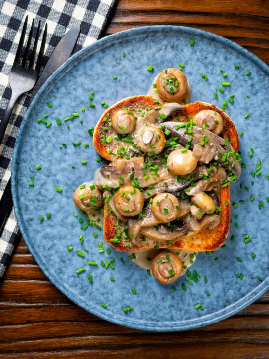 Overhead creamy garlic mushrooms on toast with portobello and button mushrooms and snipped chives.