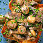 Overhead Close-up creamy garlic mushrooms on toast with snipped chives.