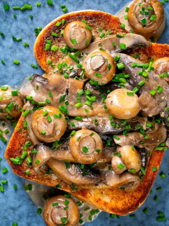 Overhead Close-up creamy garlic mushrooms on toast with snipped chives.
