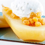 Close-up dessert wine poached pears with golden raisins and Chantilly cream.