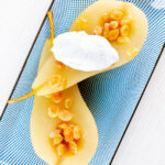 Overhead dessert wine poached pears with golden raisins and Chantilly cream.