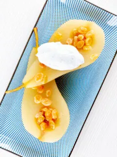 Overhead dessert wine poached pears with golden raisins and Chantilly cream.