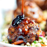 Harissa beef meatballs being drizzled with pomegranate molasses served with bulgur wheat.
