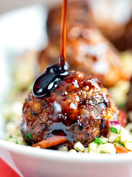 Harissa beef meatballs being drizzled with pomegranate molasses served with bulgur wheat.