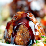 Close-up harissa beef meatballs drizzled with pomegranate molasses served with bulgur wheat.