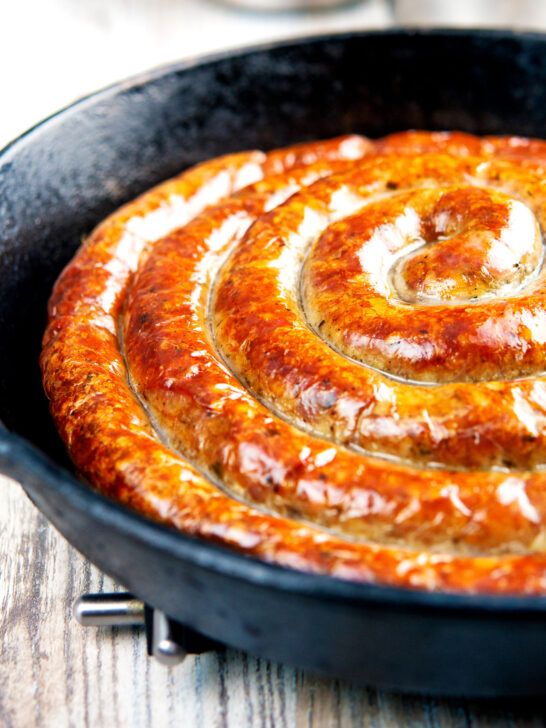 Close up cooked Cumberland sausage ring in a cast iron pan.