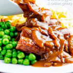 Onion gravy being poured over a piece of Cumberland sausage ring with peas and mash featuring a title overlay.